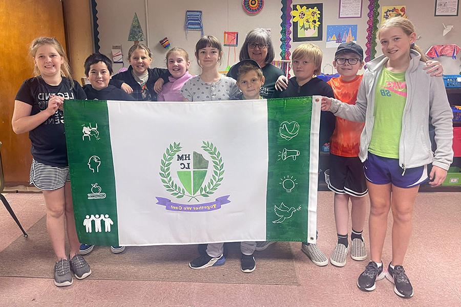 霍勒斯·曼恩的学生在萨拉·温特斯的五年级和六年级教室里, 与美术老师洛里·阿特金斯合影, 设计了一面代表他们学校的旗帜. (提交的图)